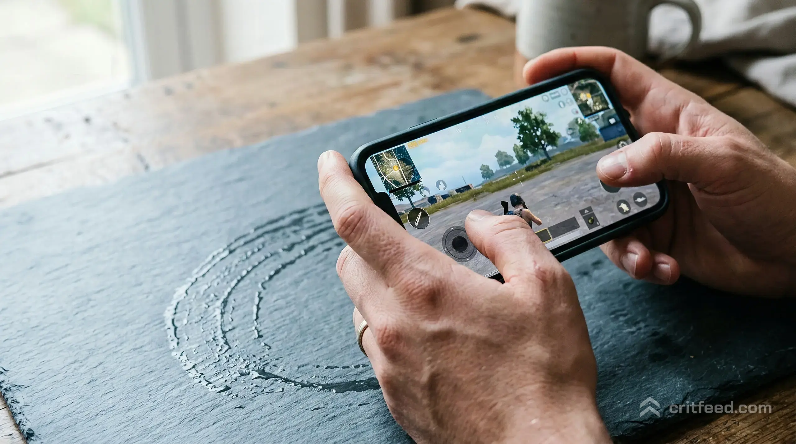 Close-up of hands gripping a smartphone in landscape orientation, thumbs resting near on-screen buttons, the phone warm