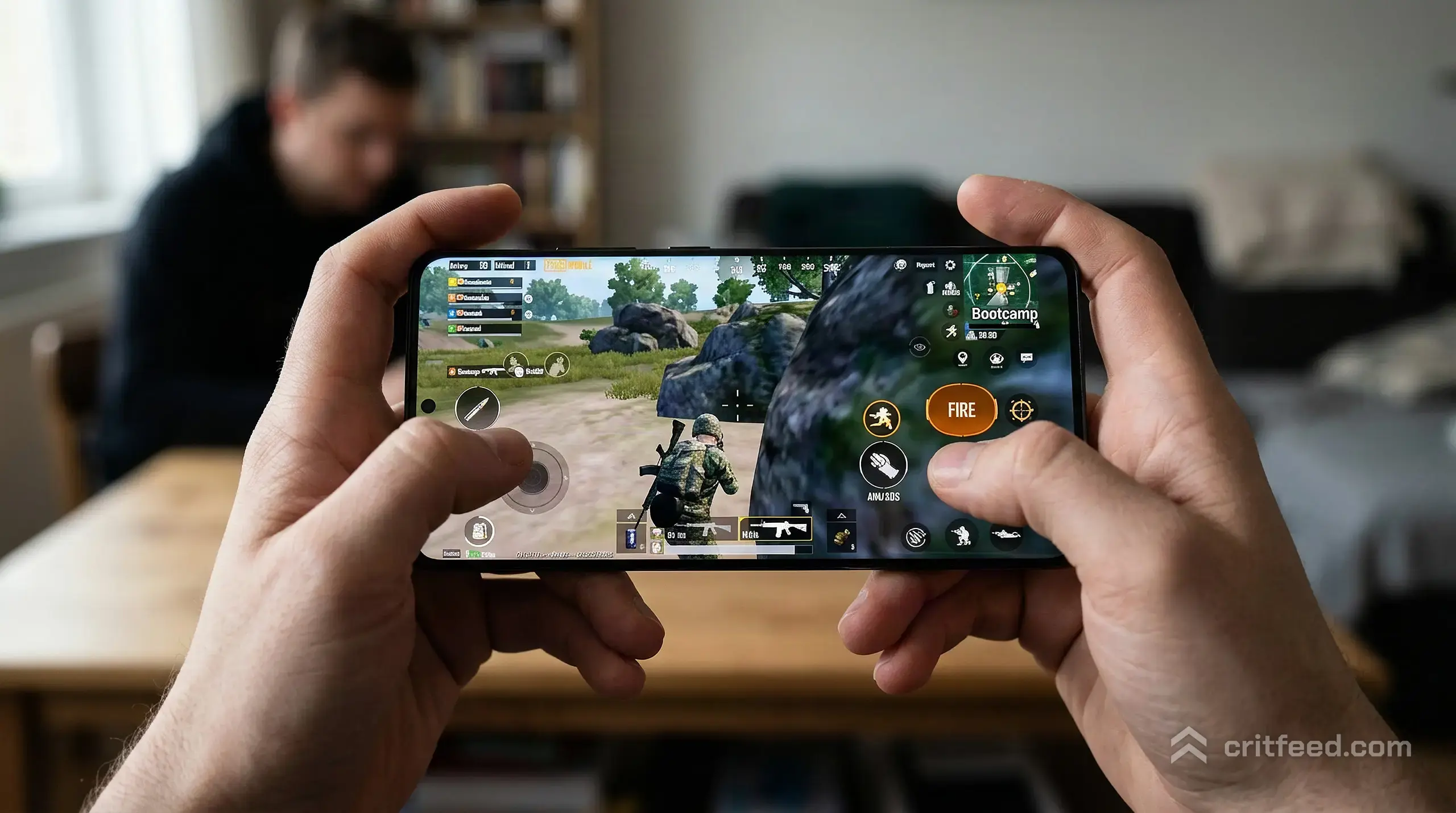 a close-up of two hands holding a modern smartphone in landscape, thumbs resting on the on-screen fire and aim buttons, soft