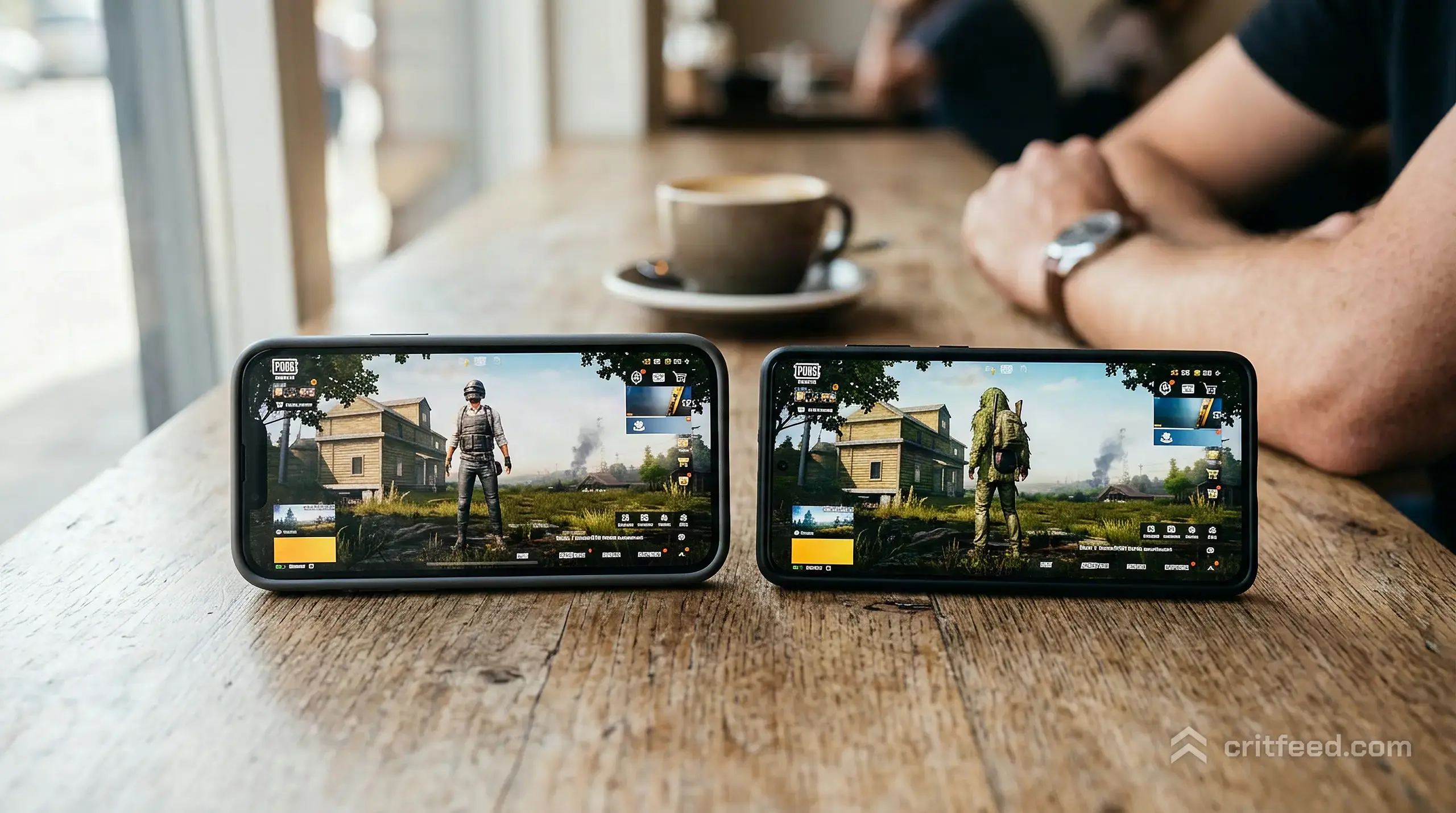 a close shot of two phones side by side on a cafe table, both showing colourful game lobby backgrounds, no readable text,